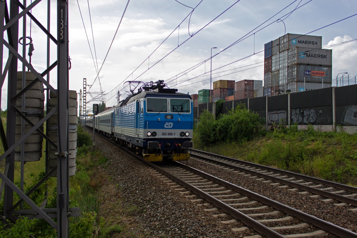 Von Česk� Budějovice kommend durchf�hrt 362 086 Praha-Horn� Měcholupy und rollt damit dem Ziel des Zuges entgegen. Hinter der L�rmschutzwand verbergen sich die Ausl�ufer des Container-Terminals Uhř�něves.